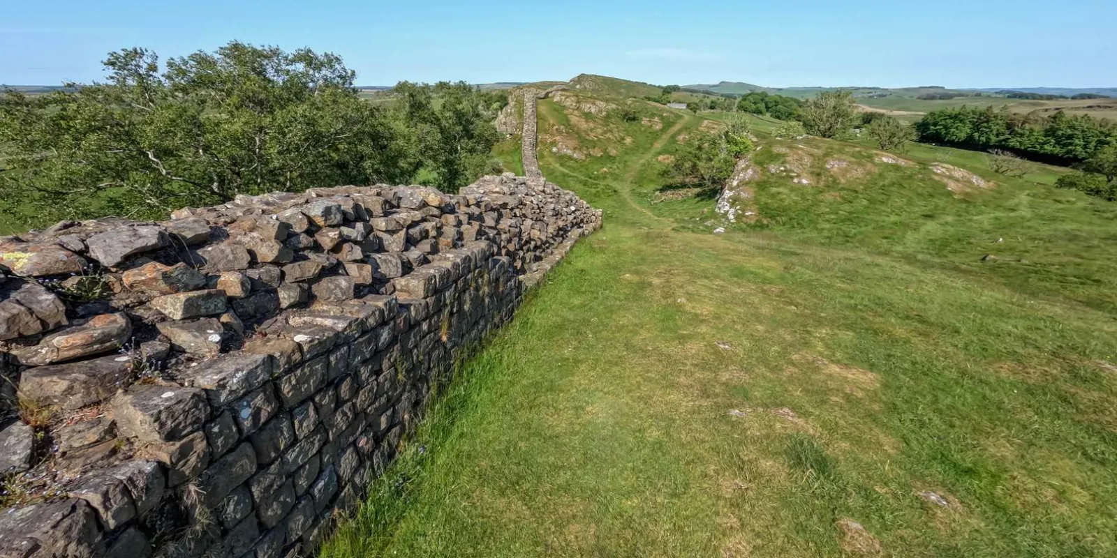 The coursed masonry of Hadrian's Wall running along the top of the Whin Sill