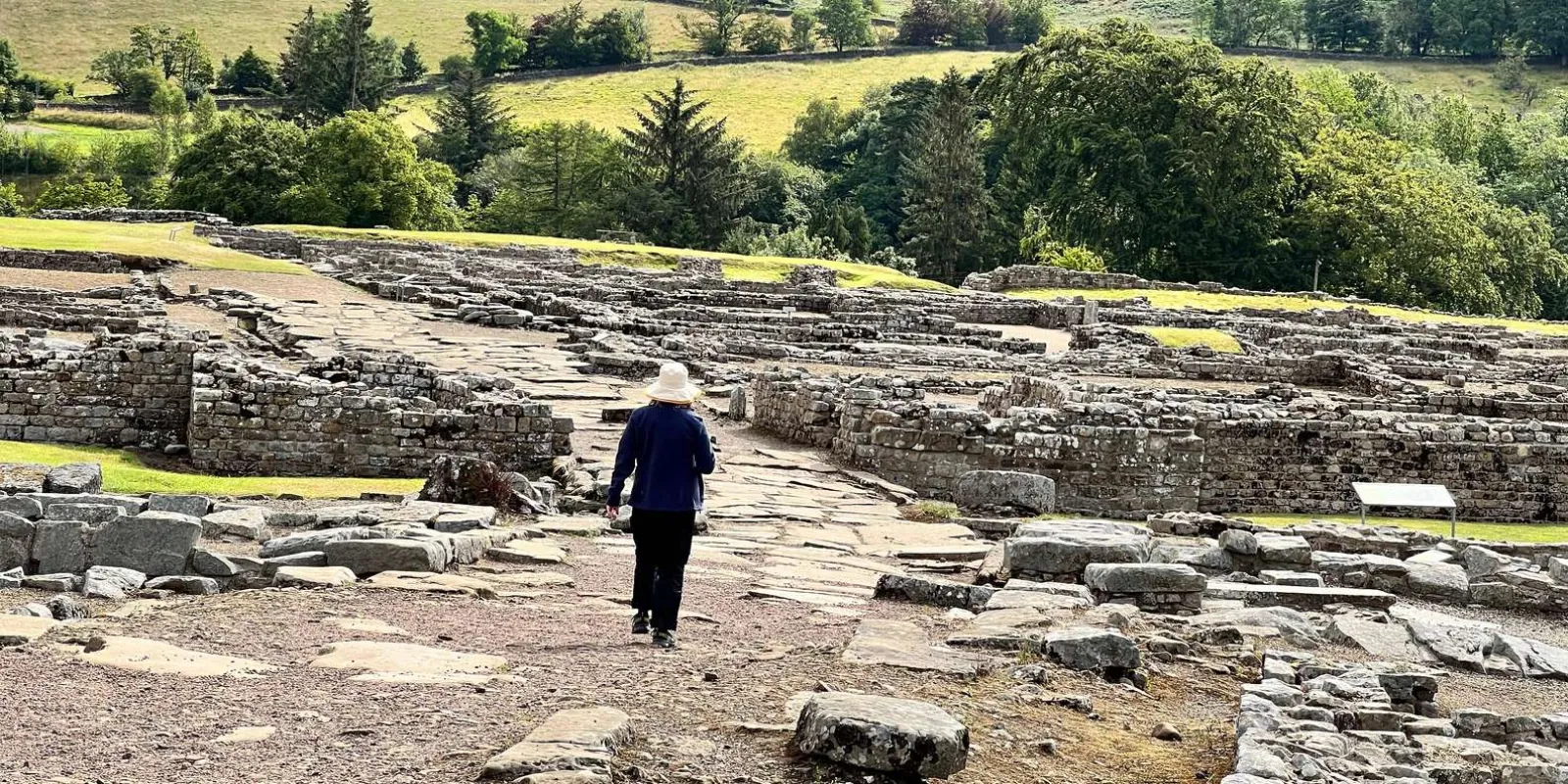 A visitor walking the excavated street of the Roman fort at Vindolanda