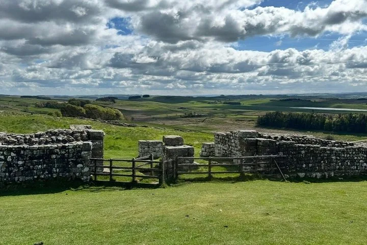 Hadrian's Wall running through open Northumberland farmland under a wide cloudy sky